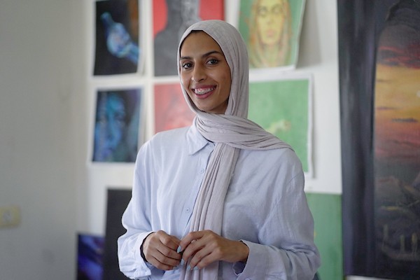 الفنانة نورة القصاص ترسم داخل غرفة بسيطة حولتها إلى مرسم في منزل أحد أقاربها بحي الشيخ رضوان في مدينة غزة، في 12 أغسطس/آب 2026. (تصوير: محمد أبو القمصان)