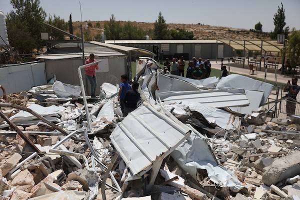 فلسطينيون يتفقدون أنقاض الجزء المهدوم من مدرسة شعب البطم الأساسية المختلطة جنوب الخليل، في مشهد يجسد التحديات التي تواجه حق الأطفال في التعليم. (تصوير: مأمون وزواز)