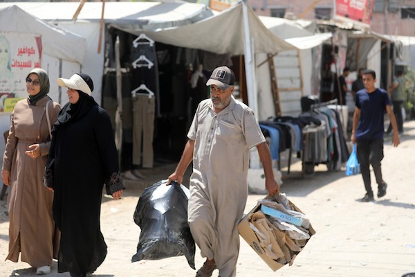 فلسطينيون نازحون يمارسون تفاصيل حياتهم اليومية بين خيام الإيواء والمباني المدمرة في شمال مدينة غزة، في 27 آب/أغسطس 2026. (تصوير: بلال أسامة)