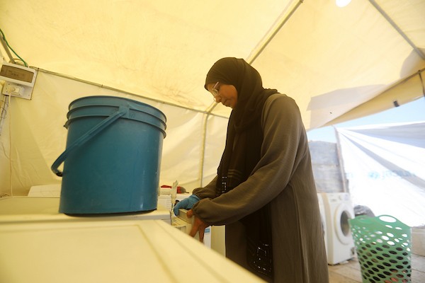 فلسطينيون يغسلون ملابسهم باستخدام غسالات كهربائية داخل مخيم للنازحين غرب مدينة غزة، في 27 أغسطس/آب 2026، وسط صعوبات في تأمين المياه والكهرباء. (تصوير: بلال أسامة)