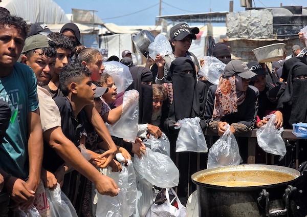 فلسطينيون ينتظرون دورهم للحصول على وجبة من مطبخ خيري في منطقة المواصي بخان يونس، جنوب قطاع غزة، في 7 أغسطس/آب 2026، وسط استمرار الأزمة الإنسانية ونقص الإمدادات الغذائية. تصوير: طارق محمد