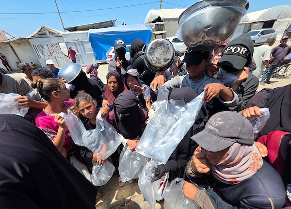 فلسطينيون ينتظرون دورهم للحصول على وجبة من مطبخ خيري في منطقة المواصي بخان يونس، جنوب قطاع غزة، في 7 أغسطس/آب 2026، وسط استمرار الأزمة الإنسانية ونقص الإمدادات الغذائية. تصوير: طارق محمد