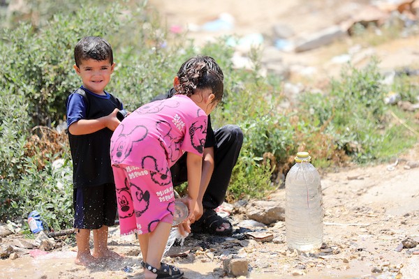 أطفال فلسطينيون نازحون يرتشفون الماء قرب مخيمات النزوح بجوار حي الشجاعية، شرق مدينة غزة، في 9 أغسطس/آب 2026، وسط ارتفاع درجات الحرارة وظروف معيشية صعبة في الخيام ومحدودية وسائل التبريد والخدمات الأساسية. (تصوير: بلال أسامة)