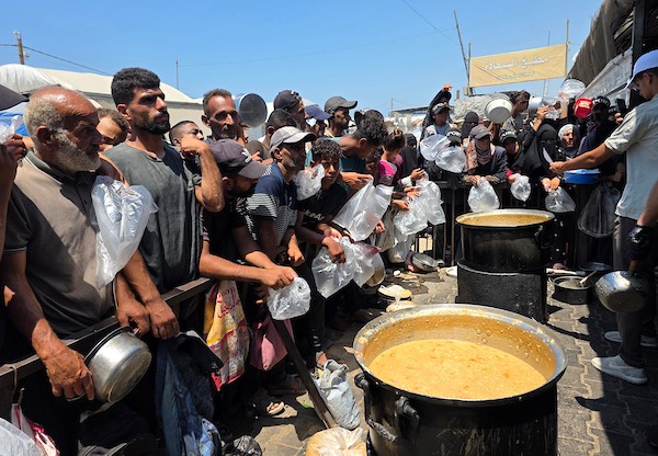 فلسطينيون ينتظرون دورهم للحصول على وجبة من مطبخ خيري في منطقة المواصي بخان يونس، جنوب قطاع غزة، في 7 أغسطس/آب 2026، وسط استمرار الأزمة الإنسانية ونقص الإمدادات الغذائية. تصوير: طارق محمد