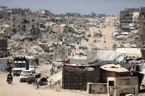 فلسطينيون يسيرون بين أنقاض المباني المدمرة في مخيم جباليا شمال قطاع غزة. تصوير: بلال أسامة
