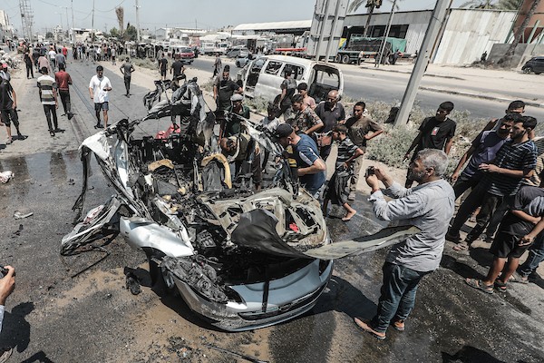 يتفقد فلسطينيون موقع غارة جوية إسرائيلية استهدفت سيارة مدنية في شارع صلاح الدين بدير البلح، وسط قطاع غزة، في 2 أغسطس/آب 2026. صورة: معز صالحي