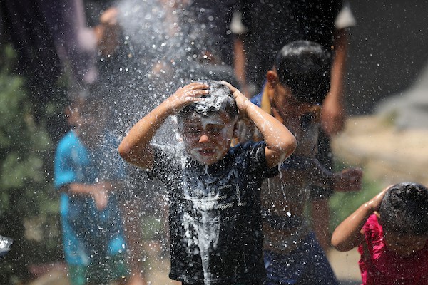 أطفال فلسطينيون نازحون يرتشفون الماء قرب مخيمات النزوح بجوار حي الشجاعية، شرق مدينة غزة، في 9 أغسطس/آب 2026، وسط ارتفاع درجات الحرارة وظروف معيشية صعبة في الخيام ومحدودية وسائل التبريد والخدمات الأساسية. (تصوير: بلال أسامة)