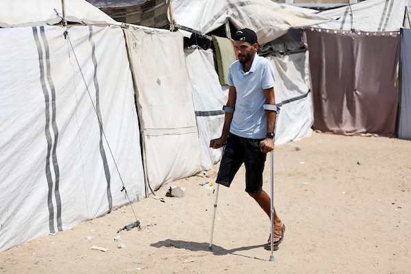 الحلاق الفلسطيني شادي البراوي، 35 عاما، يعمل داخل خيمة نزح إليها مع عائلته في مدينة غزة، في 27 آب/أغسطس 2026، بعدما فقد ساقه اليمنى إثر إصابته بشظايا خلال هجوم إسرائيلي.(تصوير: بلال أسامة)