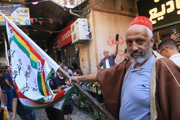 فلسطينيون بالزي التقليدي يؤدون أناشيد ومدائح دينية ويوزعون الحلوى في السوق المركزي بالبلدة القديمة في نابلس،خلال إحياء ذكرى المولد النبوي الشريف، في 25 أغسطس/آب 2026. (تصوير: محمد ناصر)