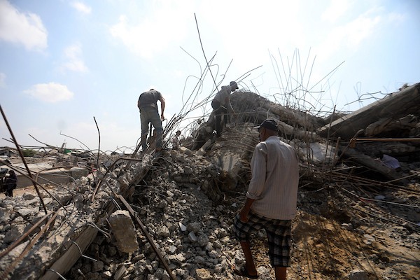عمال فلسطينيون يستخرجون الحديد من أنقاض منازل مدمرة في حي التفاح بمدينة غزة لإعادة استخدامه في تدعيم خيام ومساكن مؤقتة للنازحين. (تصوير: بلال أسامة)