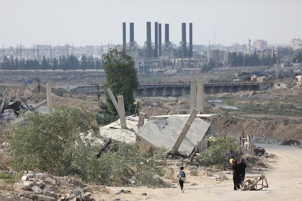 فلسطينيون يتنقلون بين أنقاض مبانٍ مدمرة في منطقة المغاري وسط قطاع غزة، في مشهد يعكس حجم الأضرار التي لحقت بالمناطق السكنية خلال الحرب. (تصوير: حسن الجدي)