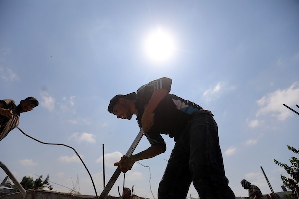 عمال فلسطينيون يستخرجون الحديد من أنقاض منازل مدمرة في حي التفاح بمدينة غزة لإعادة استخدامه في تدعيم خيام ومساكن مؤقتة للنازحين. (تصوير: بلال أسامة)