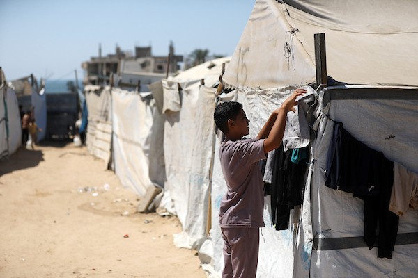 فلسطينيون يغسلون ملابسهم باستخدام غسالات كهربائية داخل مخيم للنازحين غرب مدينة غزة، في 27 أغسطس/آب 2026، وسط صعوبات في تأمين المياه والكهرباء. (تصوير: بلال أسامة)