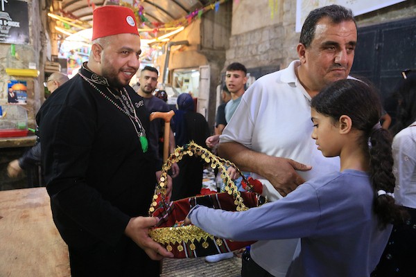 فلسطينيون بالزي التقليدي يؤدون أناشيد ومدائح دينية ويوزعون الحلوى في السوق المركزي بالبلدة القديمة في نابلس،خلال إحياء ذكرى المولد النبوي الشريف، في 25 أغسطس/آب 2026. (تصوير: محمد ناصر)