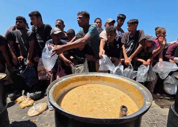 فلسطينيون ينتظرون دورهم للحصول على وجبة من مطبخ خيري في منطقة المواصي بخان يونس، جنوب قطاع غزة، في 7 أغسطس/آب 2026، وسط استمرار الأزمة الإنسانية ونقص الإمدادات الغذائية. تصوير: طارق محمد