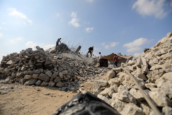 عمال فلسطينيون يستخرجون الحديد من أنقاض منازل مدمرة في حي التفاح بمدينة غزة لإعادة استخدامه في تدعيم خيام ومساكن مؤقتة للنازحين. (تصوير: بلال أسامة)