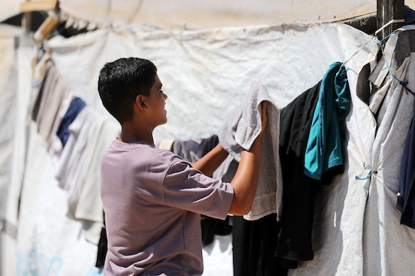 فلسطينيون يغسلون ملابسهم باستخدام غسالات كهربائية داخل مخيم للنازحين غرب مدينة غزة، في 27 أغسطس/آب 2026، وسط صعوبات في تأمين المياه والكهرباء. (تصوير: بلال أسامة)