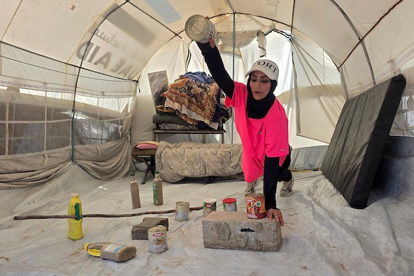 مدربة اللياقة البدنية إيمان المغير تستخدم علب طعام فارغة ومواد مهملة كأدوات رياضية خلال تدريبها داخل خيمتها في خان يونس.تصوير: طارق محمد