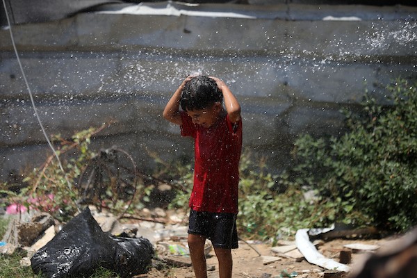 أطفال فلسطينيون نازحون يرتشفون الماء قرب مخيمات النزوح بجوار حي الشجاعية، شرق مدينة غزة، في 9 أغسطس/آب 2026، وسط ارتفاع درجات الحرارة وظروف معيشية صعبة في الخيام ومحدودية وسائل التبريد والخدمات الأساسية. (تصوير: بلال أسامة)