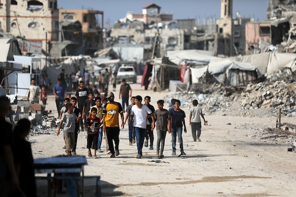 فلسطينيون يسيرون بين أنقاض المباني المدمرة في مخيم جباليا شمال قطاع غزة. تصوير: بلال أسامة