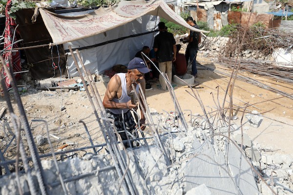 عمال فلسطينيون يستخرجون الحديد من أنقاض منازل مدمرة في حي التفاح بمدينة غزة لإعادة استخدامه في تدعيم خيام ومساكن مؤقتة للنازحين. (تصوير: بلال أسامة)