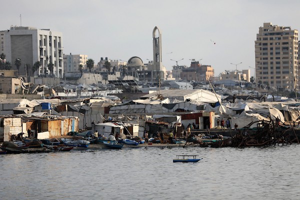عائلات فلسطينية تقضي وقتاً على شاطئ مدينة غزة هرباً من حرارة الصيف، بينما تصطف خيام النازحين بمحاذاة الساحل، في مشهد يجمع بين البحث عن لحظة راحة وثقل النزوح والحرب، 8 أغسطس/آب 2026. (تصوير: بلال أسامة)