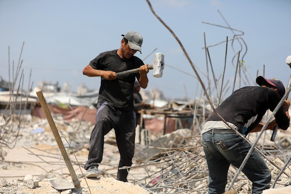 عمال فلسطينيون يستخرجون الحديد من أنقاض منازل مدمرة في حي التفاح بمدينة غزة لإعادة استخدامه في تدعيم خيام ومساكن مؤقتة للنازحين. (تصوير: بلال أسامة)