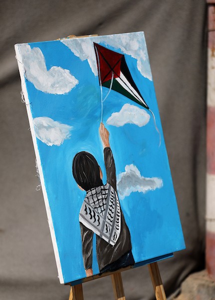 الفنان التشكيلي أحمد الحلبي يرسم طفلًا يمسك بخيط طائرة ورقية تحمل ألوان العلم الفلسطيني، أمام خيمة للنازحين في مدينة غزة،  25 أغسطس/آب 2026.  آخر.( تصوير: بلال أسامة )