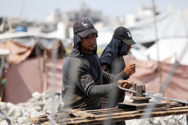 عمال فلسطينيون يستخرجون الحديد من أنقاض منازل مدمرة في حي التفاح بمدينة غزة لإعادة استخدامه في تدعيم خيام ومساكن مؤقتة للنازحين. (تصوير: بلال أسامة)