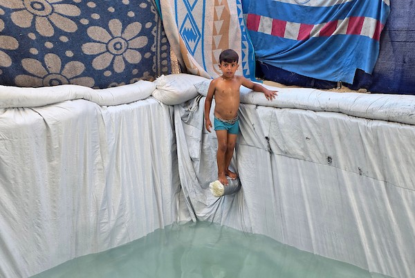 في 19 أغسطس/آب 2026، بنى الفلسطيني زكريا عبد العاطي مسبحًا صغيرًا لأطفاله باستخدام أغطية بلاستيكية من مساعدات الإغاثة في خان يونس. (صورة: طارق محمد)
