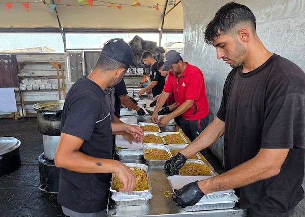 فلسطينيون ينتظرون دورهم للحصول على وجبة من مطبخ خيري في منطقة المواصي بخان يونس، جنوب قطاع غزة، في 7 أغسطس/آب 2026، وسط استمرار الأزمة الإنسانية ونقص الإمدادات الغذائية. تصوير: طارق محمد