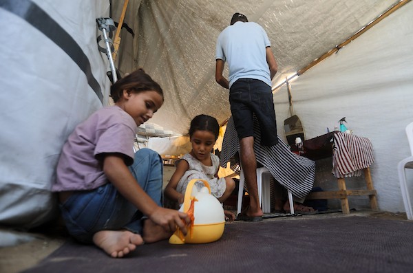 الحلاق الفلسطيني شادي البراوي، 35 عاما، يعمل داخل خيمة نزح إليها مع عائلته في مدينة غزة، في 27 آب/أغسطس 2026، بعدما فقد ساقه اليمنى إثر إصابته بشظايا خلال هجوم إسرائيلي.(تصوير: بلال أسامة)
