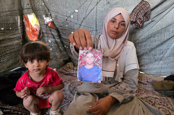 الفلسطينية فاطمة النجار تحمل صورة شقيقها محمد داخل خيمة للنازحين في خان يونس، جنوب قطاع غزة، في 30 أغسطس/آب 2026، بينما تواصل انتظار أي خبر عن مصيره في اليوم الدولي للمفقودين. تصوير: طارق محمد