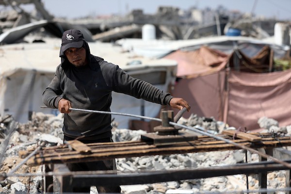 عمال فلسطينيون يستخرجون الحديد من أنقاض منازل مدمرة في حي التفاح بمدينة غزة لإعادة استخدامه في تدعيم خيام ومساكن مؤقتة للنازحين. (تصوير: بلال أسامة)