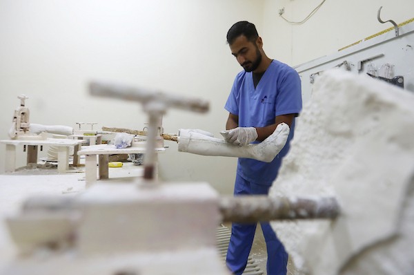 أخصائيون فلسطينيون يصنعون ويجهزون أطرافًا اصطناعية لجرحى الحرب ومبتوري الأطراف في مركز تديره بلدية غزة بمدينة غزة، في 11 أغسطس/آب 2026. (صورة: بلال أسامة)