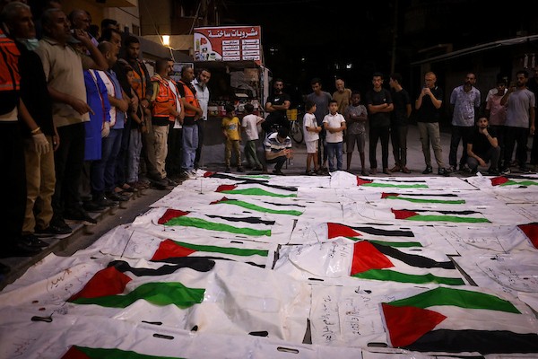 فلسطينيون يشعلون الشموع أمام مستشفى العودة في مخيم النصيرات وسط قطاع غزة، في 28 سبتمبر/أيلول 2026، خلال وداع رفات شهداء. (صورة: معز صالحي)