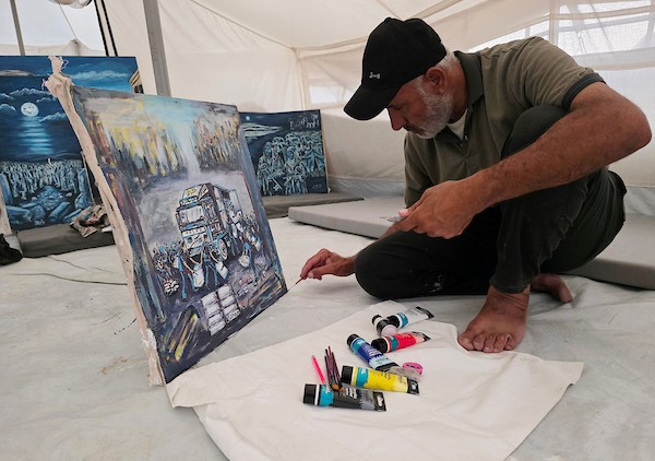 الفنان الفلسطيني جهاد الشرافي يرسم داخل خيمة للنازحين في خان يونس جنوبي قطاع غزة، مشاهد توثق الحرب والجوع ونقص المياه والدمار، في 18 سبتمبر/أيلول 2026. تصوير: طارق محمد