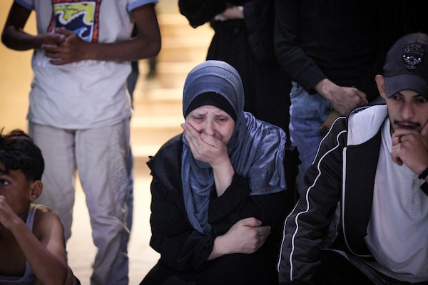 فلسطينيون يشعلون الشموع أمام مستشفى العودة في مخيم النصيرات وسط قطاع غزة، في 28 سبتمبر/أيلول 2026، خلال وداع رفات شهداء. (صورة: معز صالحي)