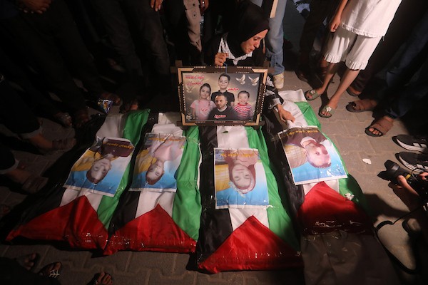فلسطينيون يتجمعون حول رفات 106 ضحايا غُطيت بالأعلام الفلسطينية وأضيئت إلى جانبها الشموع، خلال مراسم وداع في حي الزيتون بمدينة غزة، 5 أيلول/سبتمبر 2026. تصوير: بلال أسامة