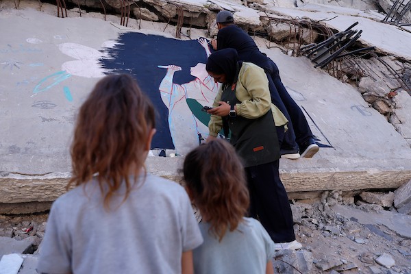 فنانون فلسطينيون يرسمون جدارية لمغني الراب الأمريكي ماكليمور على جدار مبنى دمرته الحرب في مدينة غزة، في 17 سبتمبر/أيلول 2026. تصوير: عبد الله أبو الخير