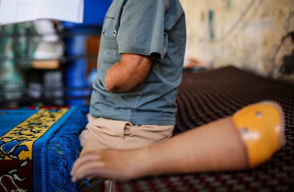 الطفل الفلسطيني كنان أبو جبة، الناجي الوحيد من عائلته بعد استهداف منزلهم في حي الشجاعية، يكتب في دفتره داخل خيمة بمدينة غزة مستخدمًا طرفًا صناعيًا بعد بتر يده اليسرى، 21 سبتمبر/أيلول 2026. تصوير: بلال أسامة.