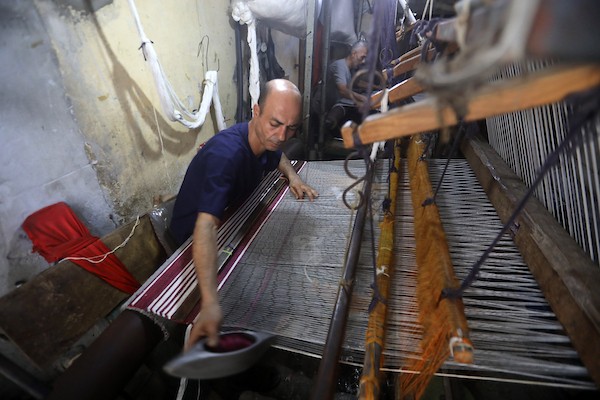 عمال فلسطينيون يصنعون السجاد يدويًا باستخدام أدوات بسيطة داخل متجر شرقي مدينة غزة، في 31 آب/أغسطس 2026. (تصوير: بلال أسامة)