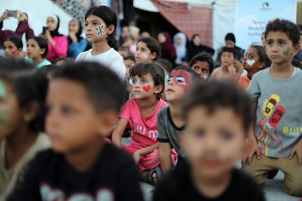 تجمّع أطفال فلسطينيون لمشاهدة عرض فيلم كرتوني في الهواء الطلق على شاشة نُصبت بين المباني المتضررة في مخيم للنازحين بحي النصر في مدينة غزة، وذلك في 2 سبتمبر/أيلول 2026.(صورة: بلال أسامة)