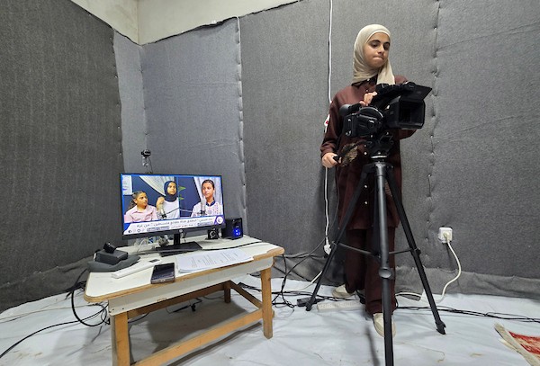 أطفال فلسطينيون يشاركون في إعداد وتقديم برامج لقناة طلائع فلسطين من استوديو متواضع أُقيم داخل خيام النزوح في منطقة مواصي خان يونس. (تصوير: طارق محمد)
