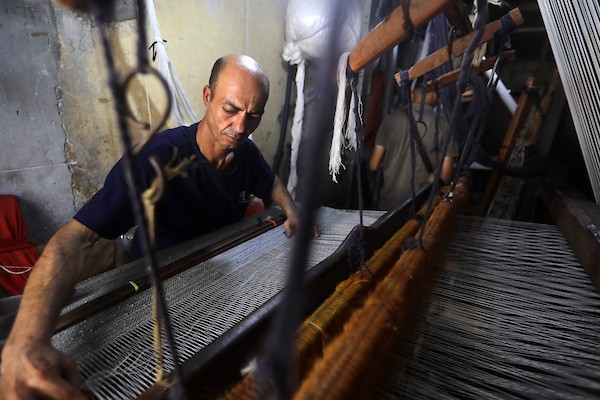 عمال فلسطينيون يصنعون السجاد يدويًا باستخدام أدوات بسيطة داخل متجر شرقي مدينة غزة، في 31 آب/أغسطس 2026. (تصوير: بلال أسامة)