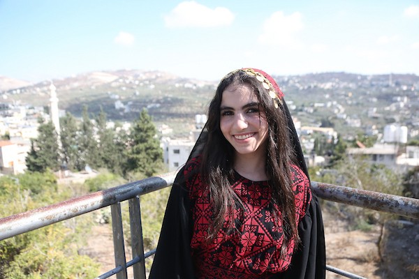 فتيات فلسطينيات يرتدين أزياءً وطنية تقليدية مطرزة بالحرير يقفن على جسر حديدي في الموقع الأثري بمدينة سبسطية، غرب نابلس شمال الضفة الغربية. (تصوير: محمد ناصر )