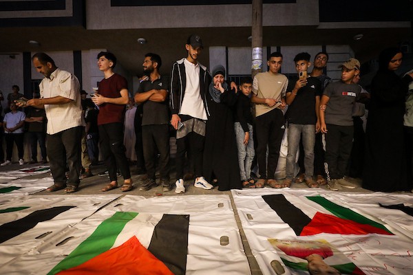 فلسطينيون يشعلون الشموع أمام مستشفى العودة في مخيم النصيرات وسط قطاع غزة، في 28 سبتمبر/أيلول 2026، خلال وداع رفات شهداء. (صورة: معز صالحي)