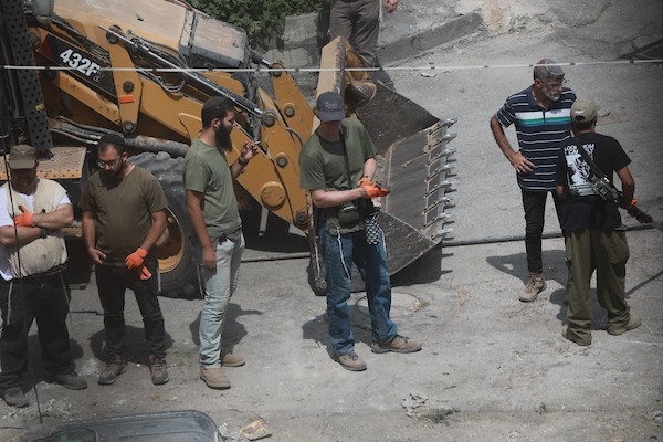 مستوطنون ينفذون أعمال تجريف في شارع الشلالة في البلدة القديمة بالخليل، بحماية قوات الاحتلال، في 31 آب/أغسطس 2026. (تصوير: مأمون وزواز)
