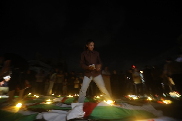 فلسطينيون يتجمعون حول رفات 106 ضحايا غُطيت بالأعلام الفلسطينية وأضيئت إلى جانبها الشموع، خلال مراسم وداع في حي الزيتون بمدينة غزة، 5 أيلول/سبتمبر 2026. تصوير: بلال أسامة