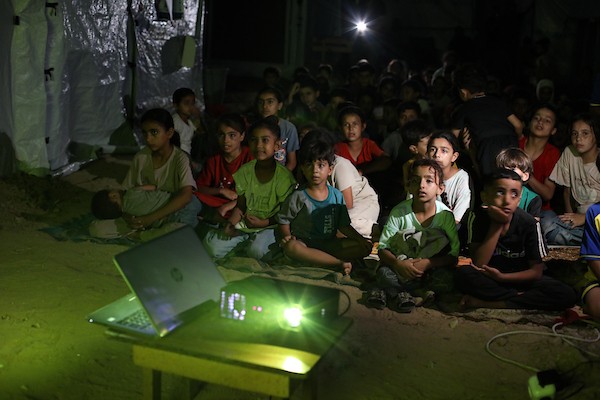أطفال فلسطينيون يشاهدون رسومًا متحركة في مخيم النصيرات للاجئين وسط قطاع غزة، في 18 سبتمبر/أيلول 2026. تصوير: حسن الجدي